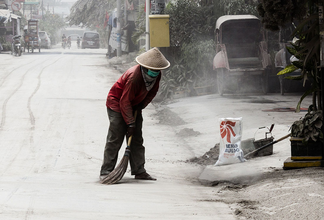 A man sweeping up volcanic ash
