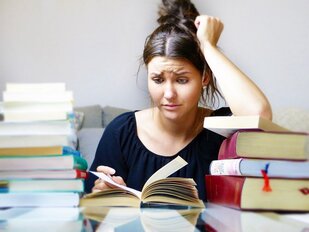 Woman reading a book and looking confused