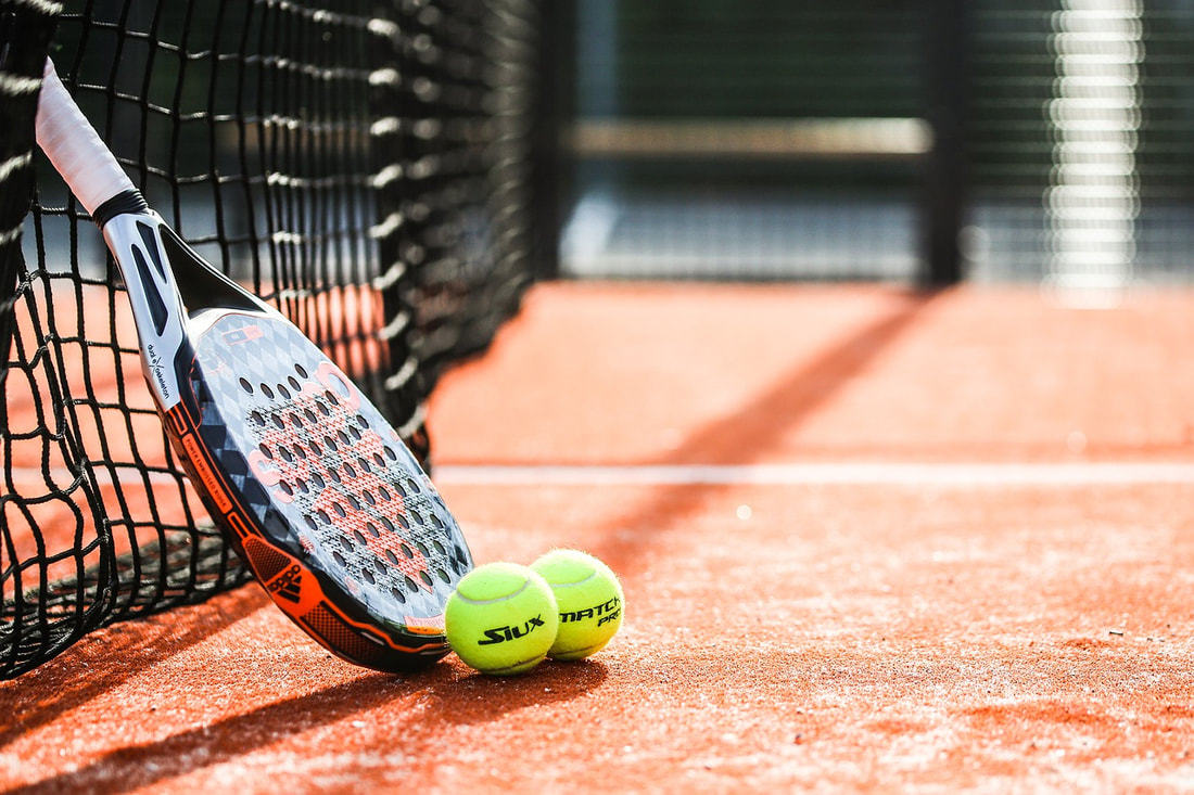 Tennis racket and balls next to a net
